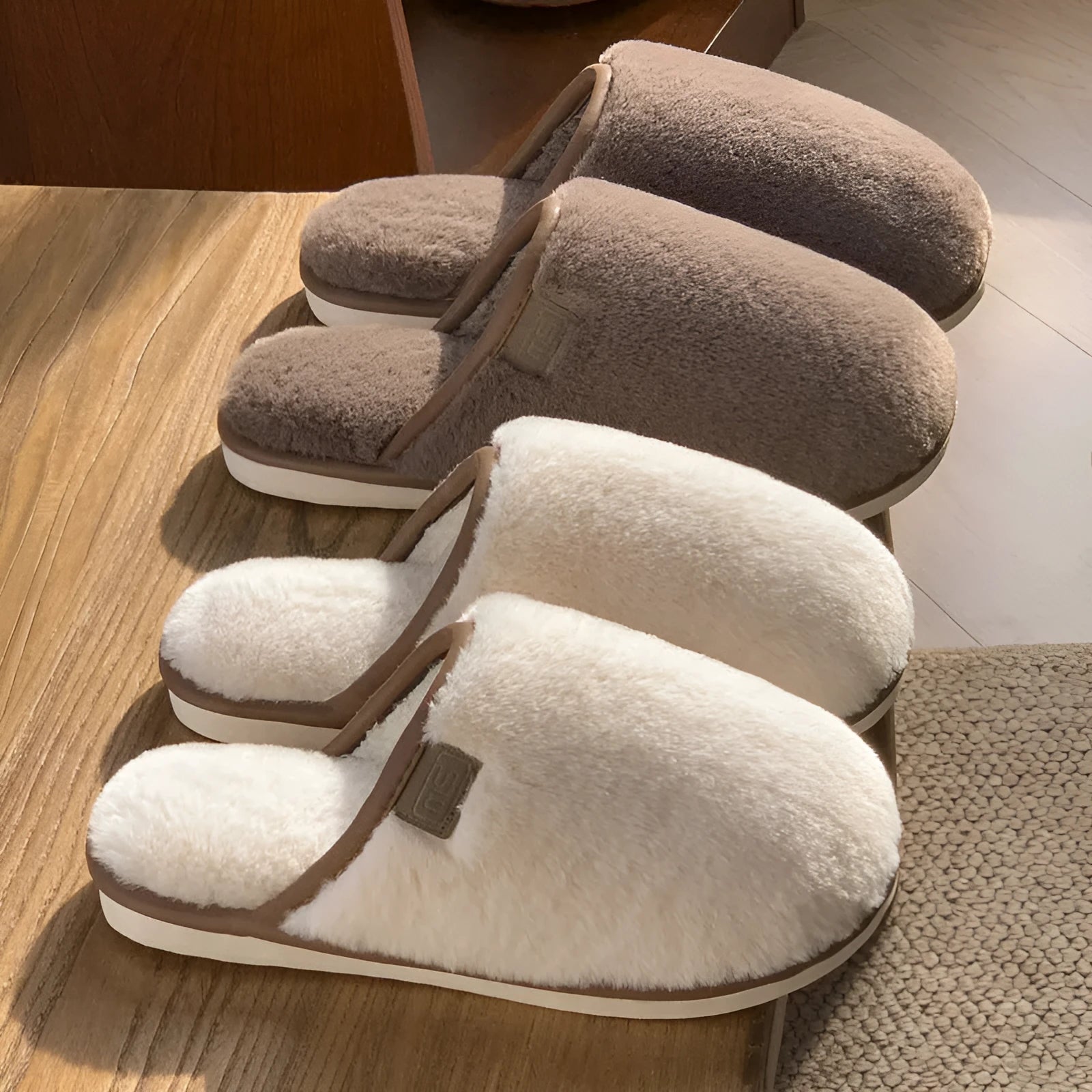A pair of solid colour winter plush slippers with a PVC sole on a wooden floor.