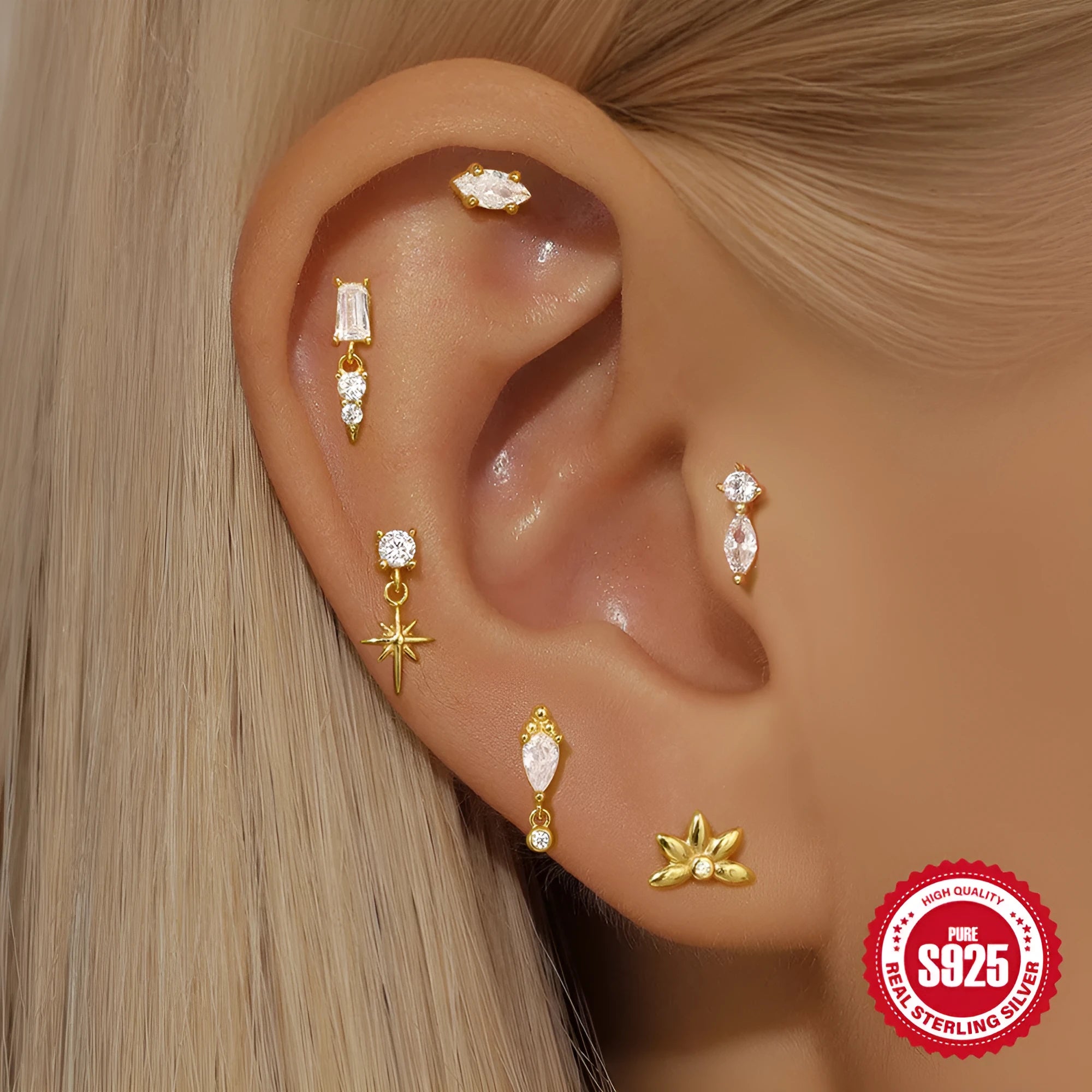 A gold tone sterling silver ear stud featuring a dangling tassel and XINGX inlaid design on the stud.