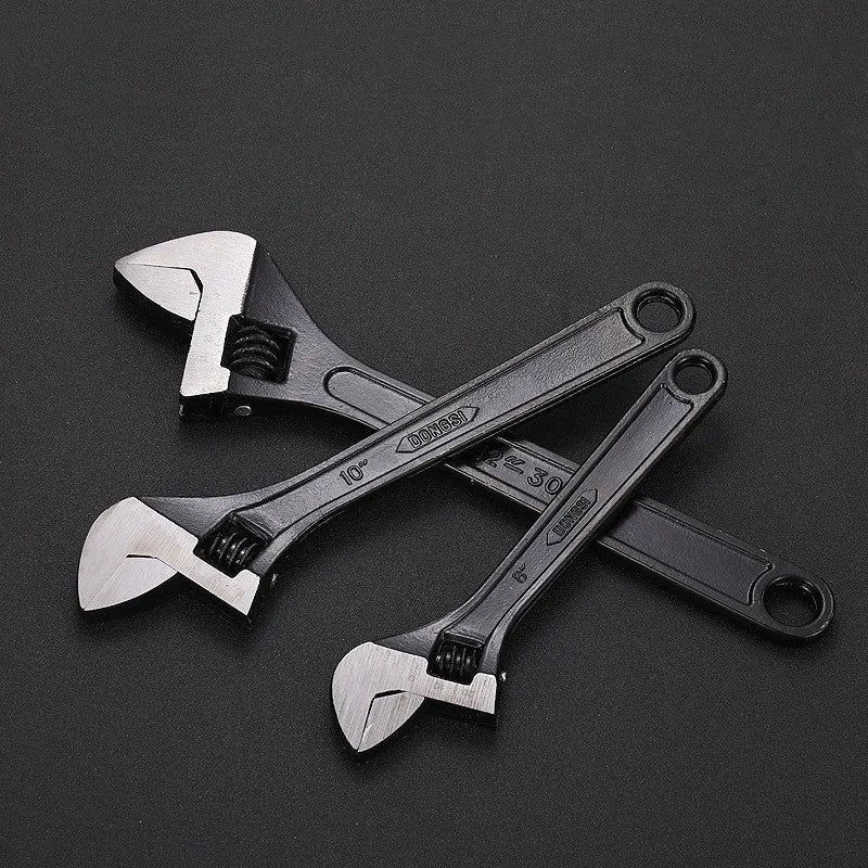 High carbon steel adjustable open-end wrench with black finish on a workbench.