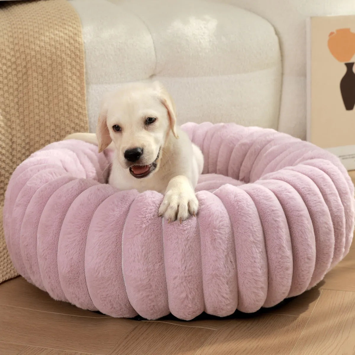 A round, plush beige pet nest bed for cats or dogs on a wooden floor.