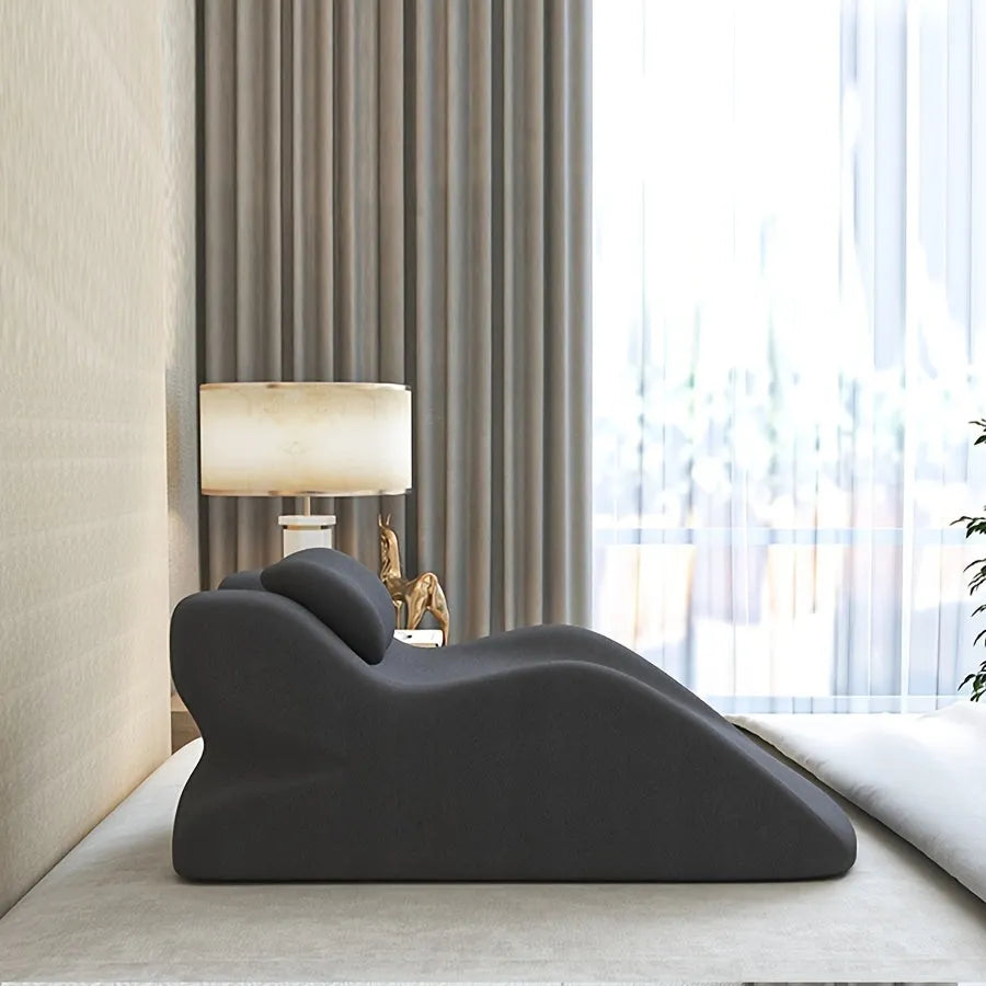 A prone position stomach sleeping pillow shown in a light grey colour, designed for use while reading in bed.