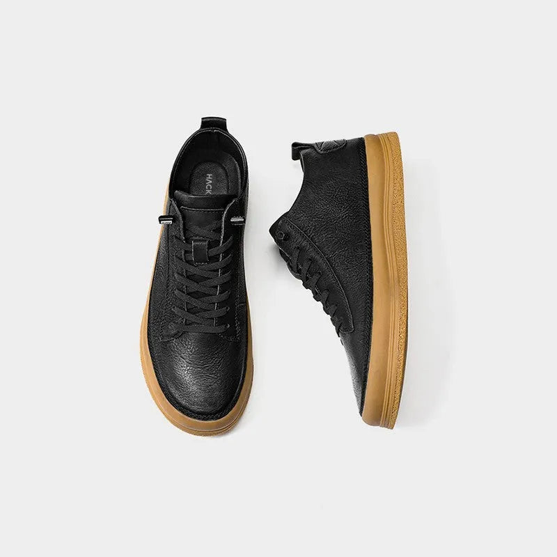 A pair of black men's round-toe casual leather shoes with white laces on a flat rubber sole.