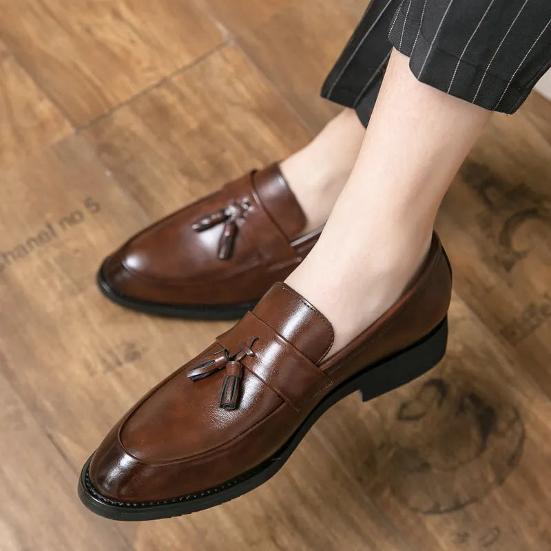 Men's black slip-on business casual shoes with a tassel detail on the front.