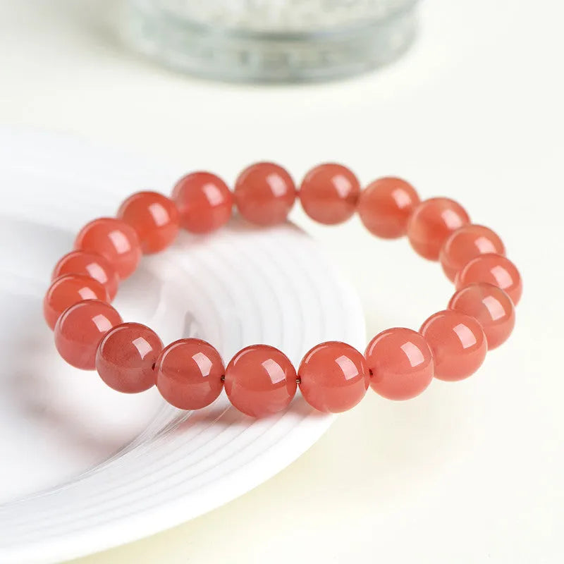 Natural cherry red agate bracelet with polished beads in a scattered design on a wrist.