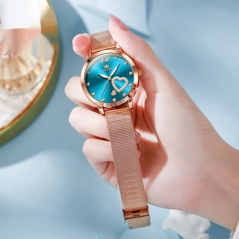 Rose gold-tone women's watch with a mesh strap showing white, black, blue, red, pink, and green dial colour options.