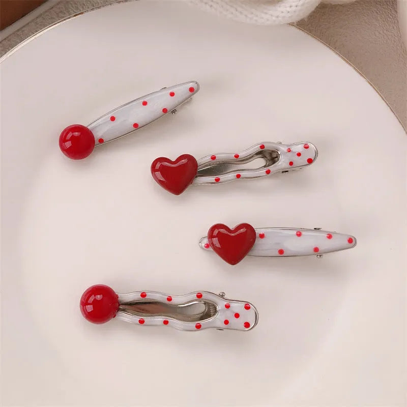 Red love heart-shaped hair clip with white polka dots and a green willow leaf decoration.