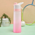 White 700ml plastic spray water bottle with a black handle strap and leakproof lid on a table.
