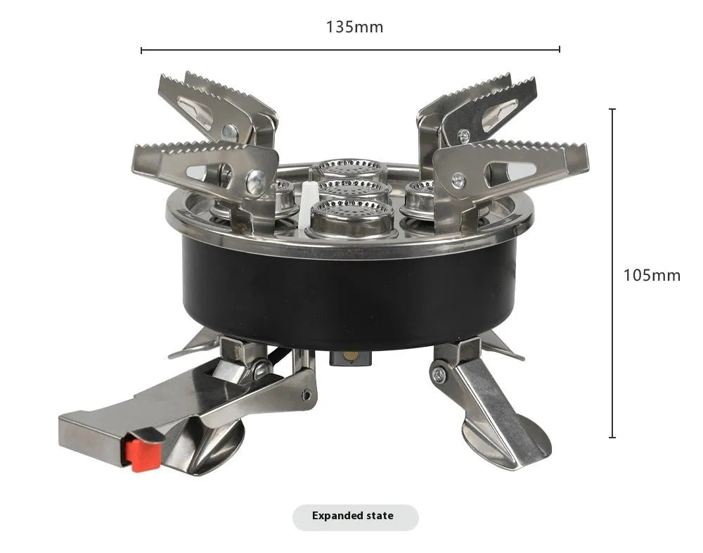 Silver portable split camping stove with foldable legs and a long black hose, on a grass background.