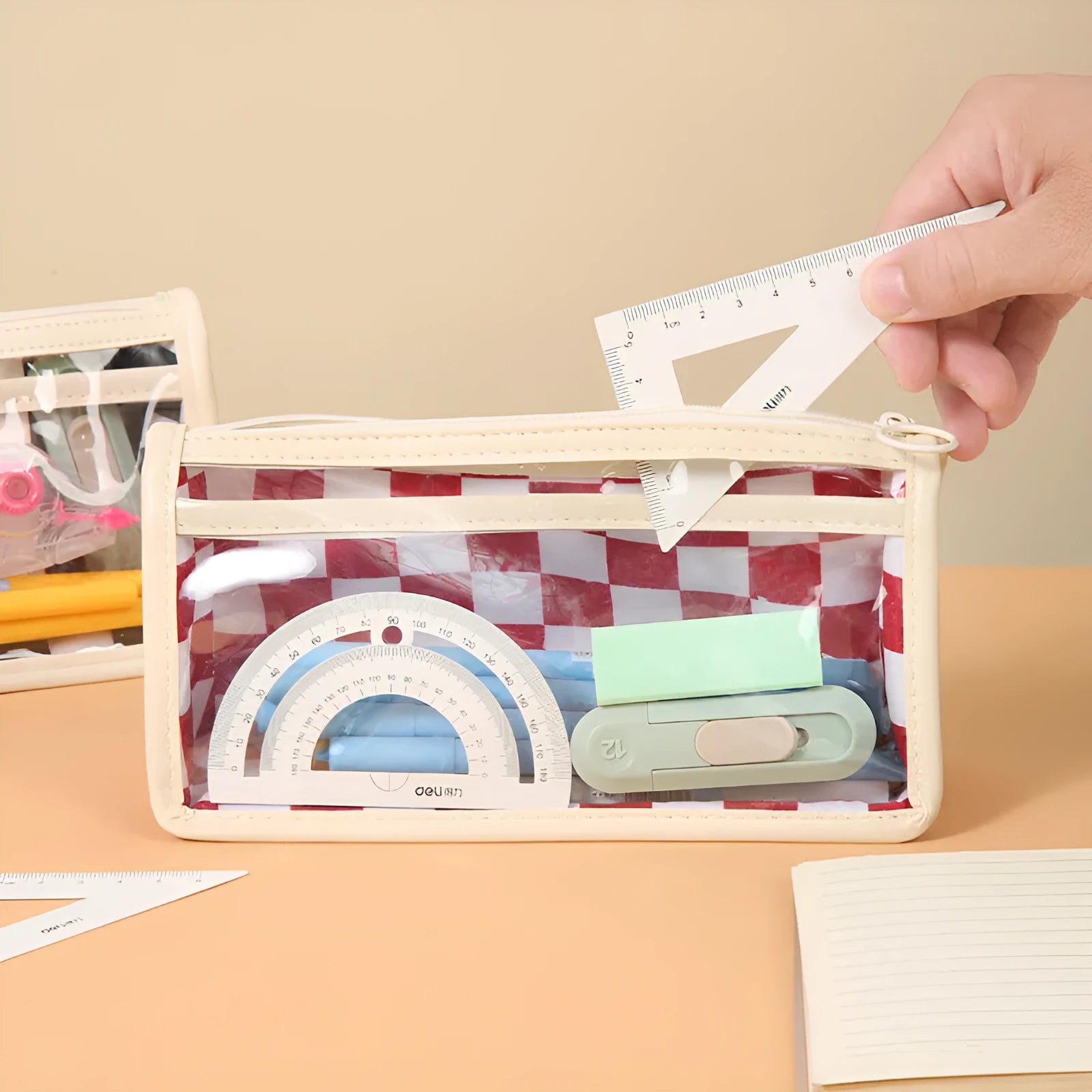 Transparent PVC pencil case with chessboard pattern, open to show large interior for pens.