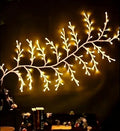 Flexible LED willow vine light garland with warm white bulbs shaped on a wall.