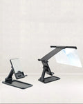Black foldable mobile phone screen magnifier with a detachable phone holder on a desk.