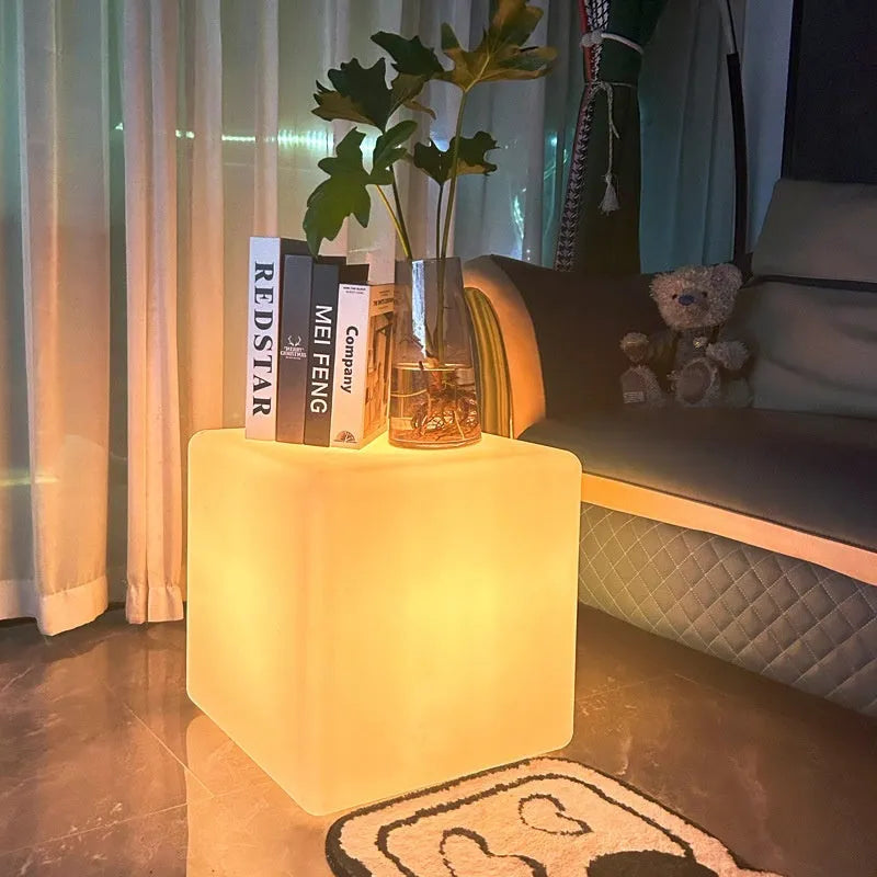 White square LED cube stool light on patio, modern outdoor seating with integrated lighting.