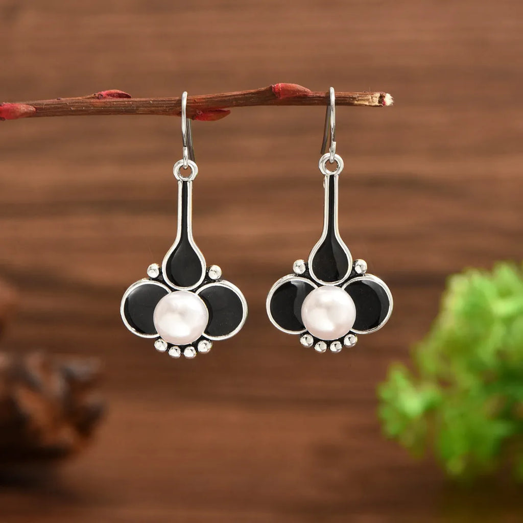 A pair of retro-style silver-coloured alloy earrings for women on a plain background.
