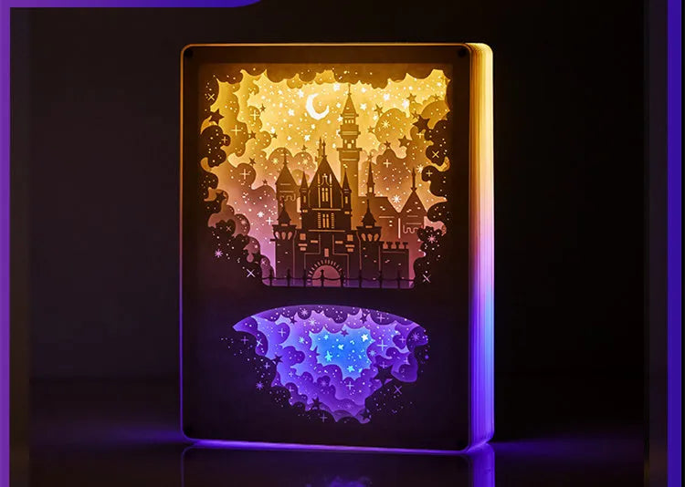 Modern three-dimensional paper carving night light with USB cable and remote control on a bedside table.