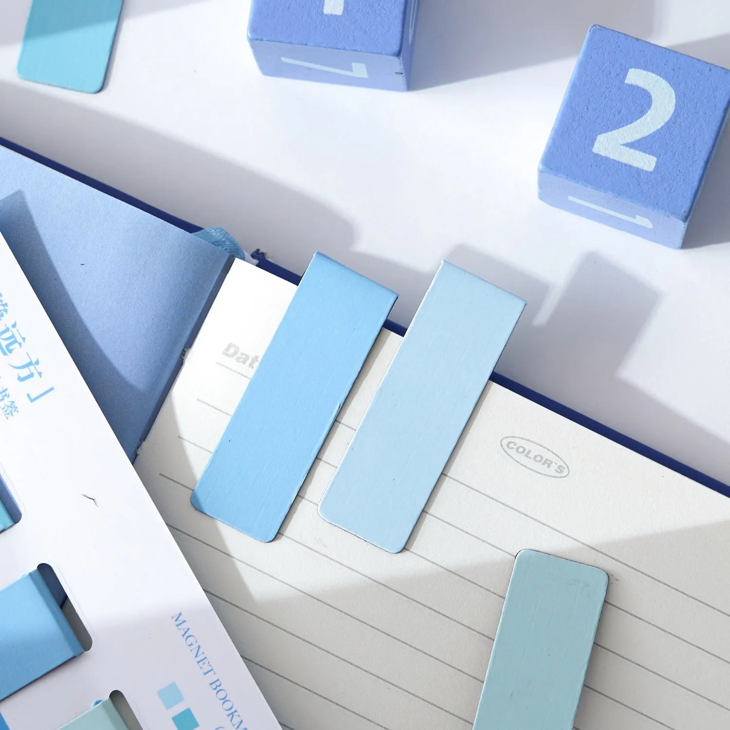 Set of four pastel colour block magnetic bookmarks from the Morandi series on a book page.