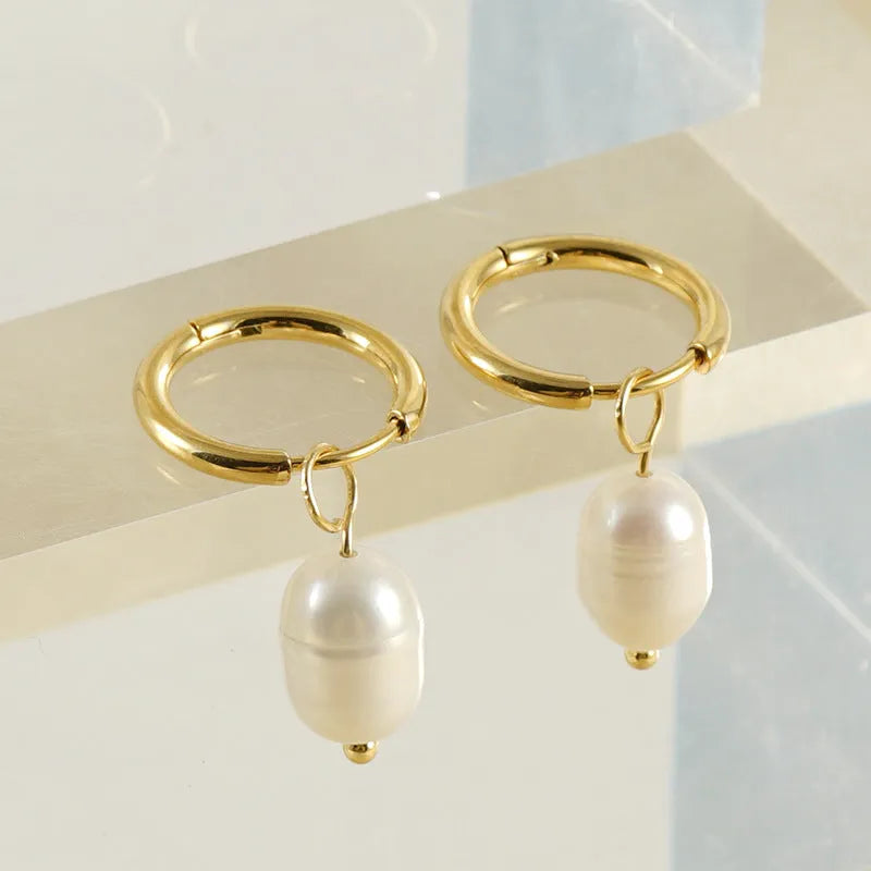 Gold geometric stainless steel earrings with a central white cultured pearl on a post.