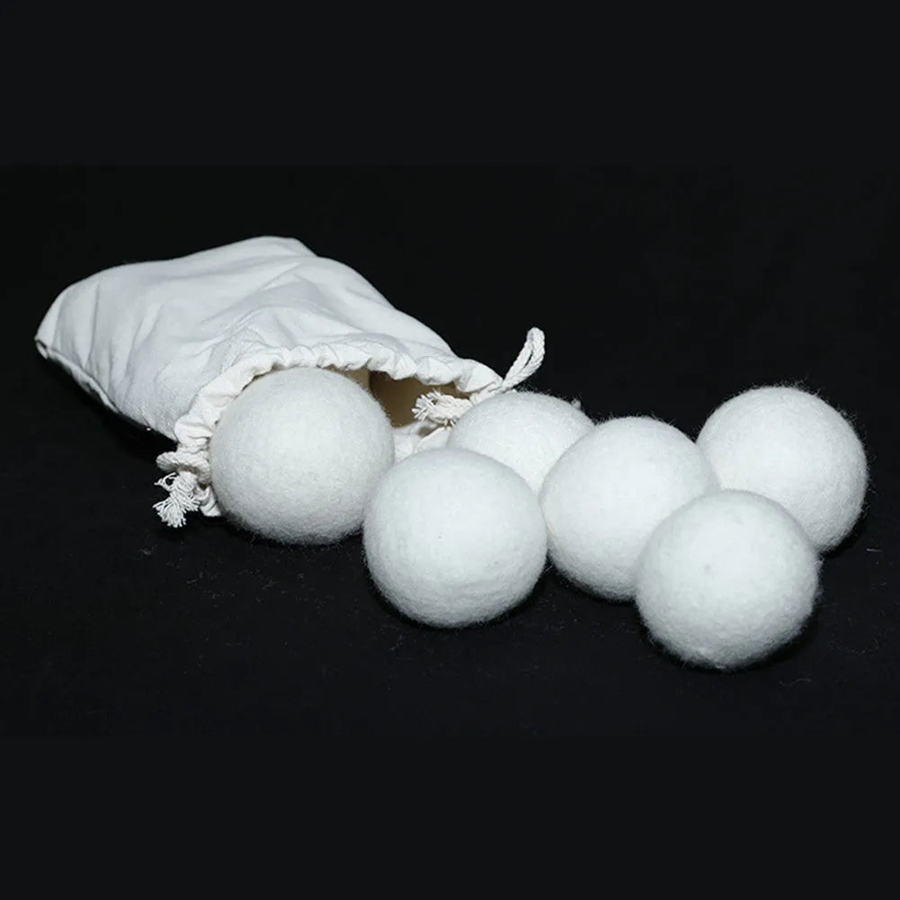 A natural wool drying ball for tumble dryers next to a plain cotton storage bag on a laundry background.