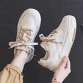Pink and white low-top spring sneakers with rubber sole on a plain background
