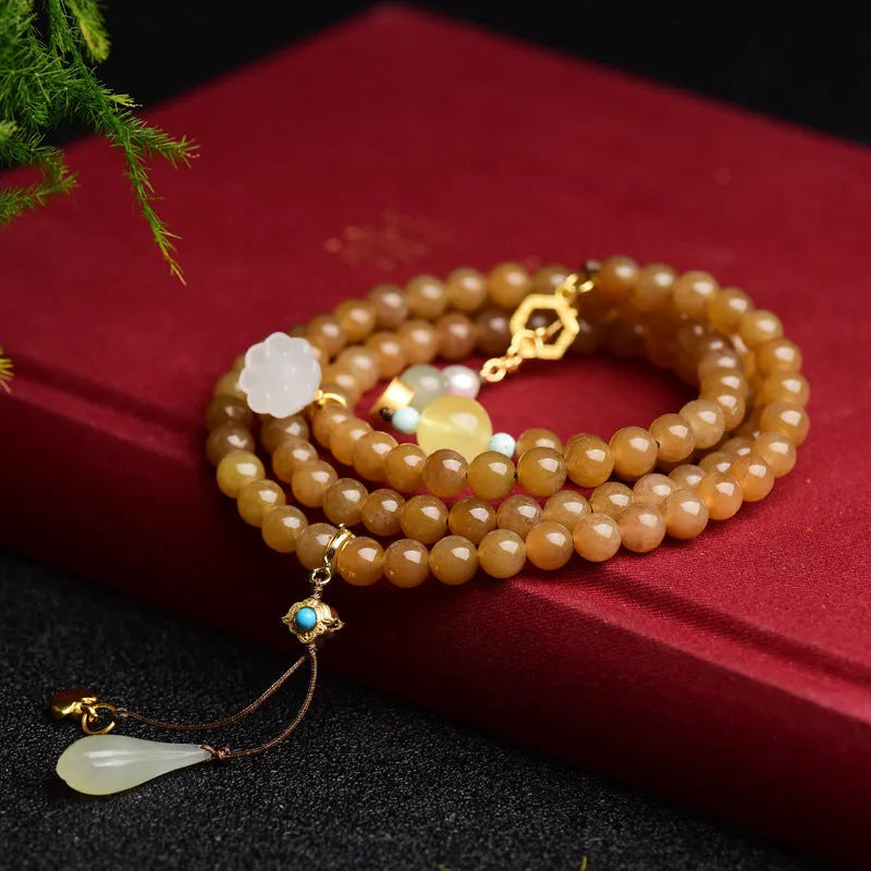 Close-up of a women's green jade bracelet with 6mm beads, beeswax, and leaf charms on a wrist.