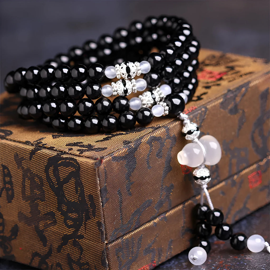 Natural black and red agate 108 bead bracelet with geometric shapes on a wrist.