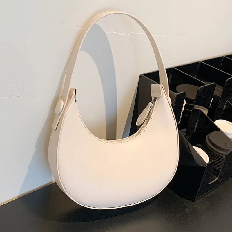 Women's retro-style PU dumpling shoulder bag in black, showing front zipper compartment.