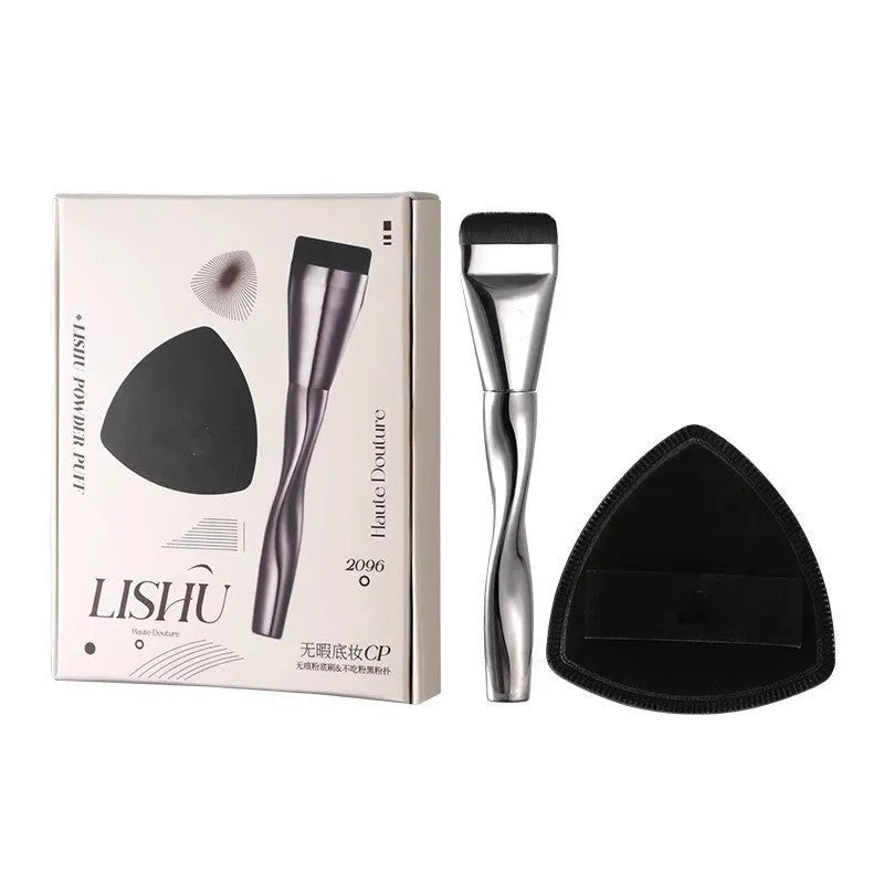 Spiral-shaped black powder foundation brush with long handle and puff on a pineapple-print box.