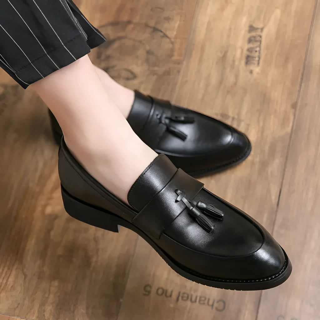 Men's black slip-on business casual shoes with a tassel detail on the front.