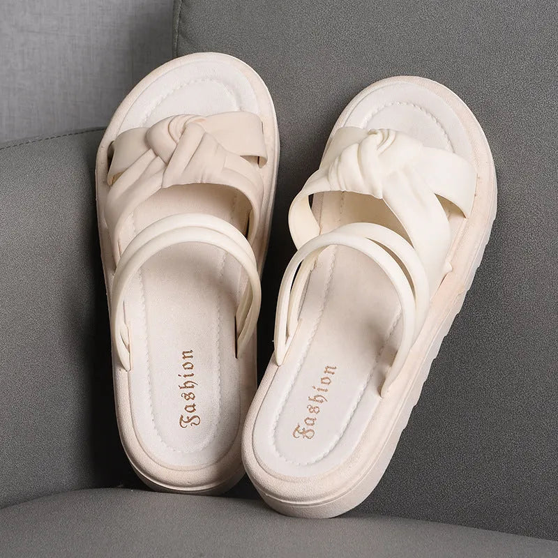 Women's black PVC sandals with soft back, floral detail, and a thick height-increasing sole.