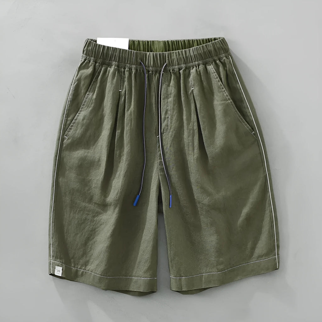 Man wearing green linen drooping shorts with a drawstring waist and mid-calf length.