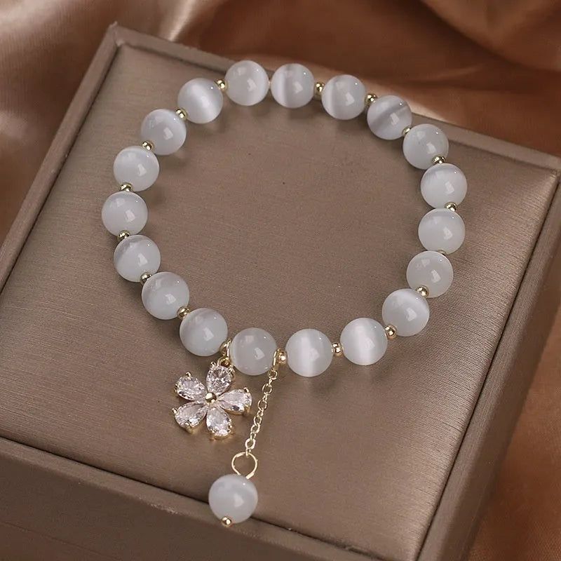 White cat's eye stone bracelet with flower tassel detailing and safety buckle closure