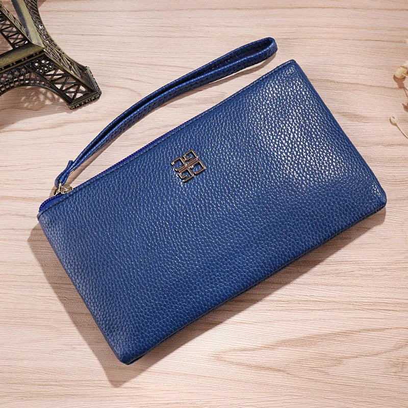 Woman holding a wine red zip-around PU leather phone wallet handbag with a 55-inch long strap.