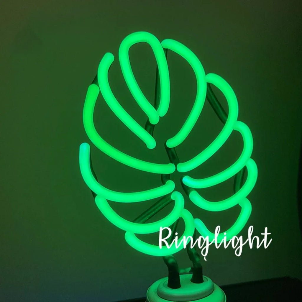 Minimalist bamboo-shaped white desk lamp with green glowing tube on a wooden table.