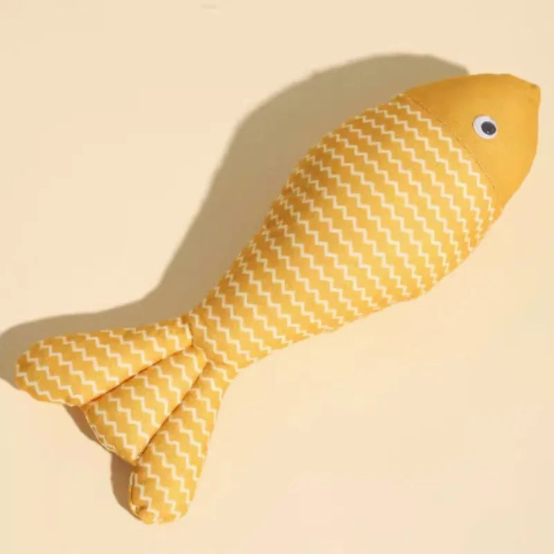 Yellow catnip fish plush chew toy for cats lying on a wooden floor.
