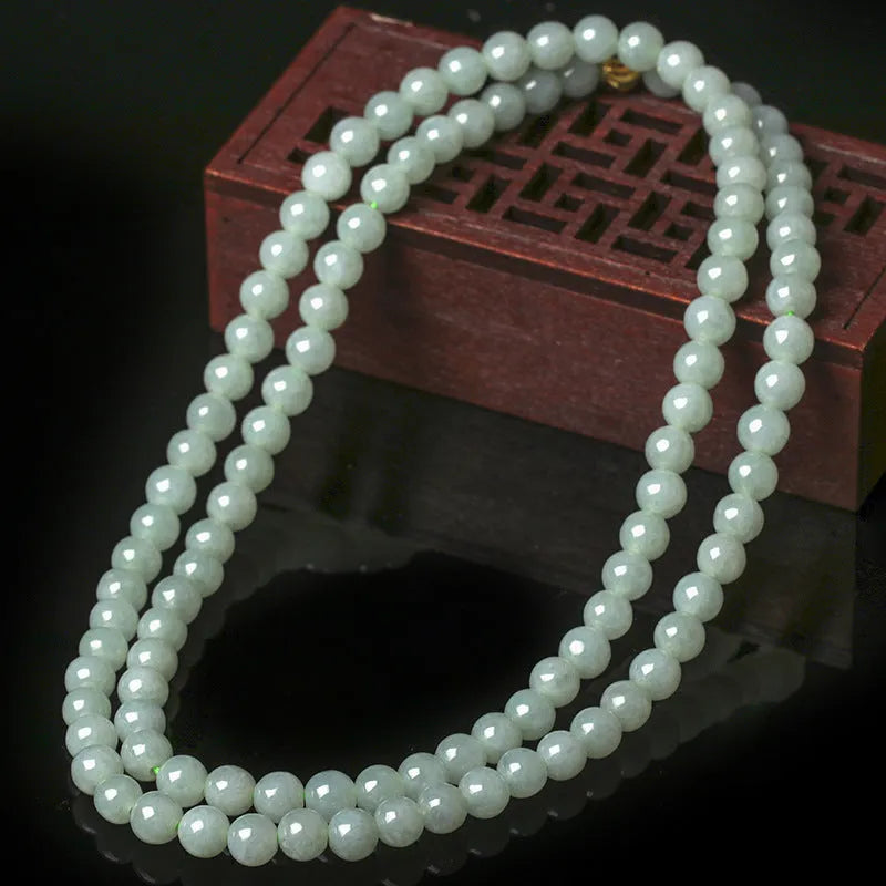 Close-up of a women's adjustable necklace with round white and green natural jade beads on a metal chain.