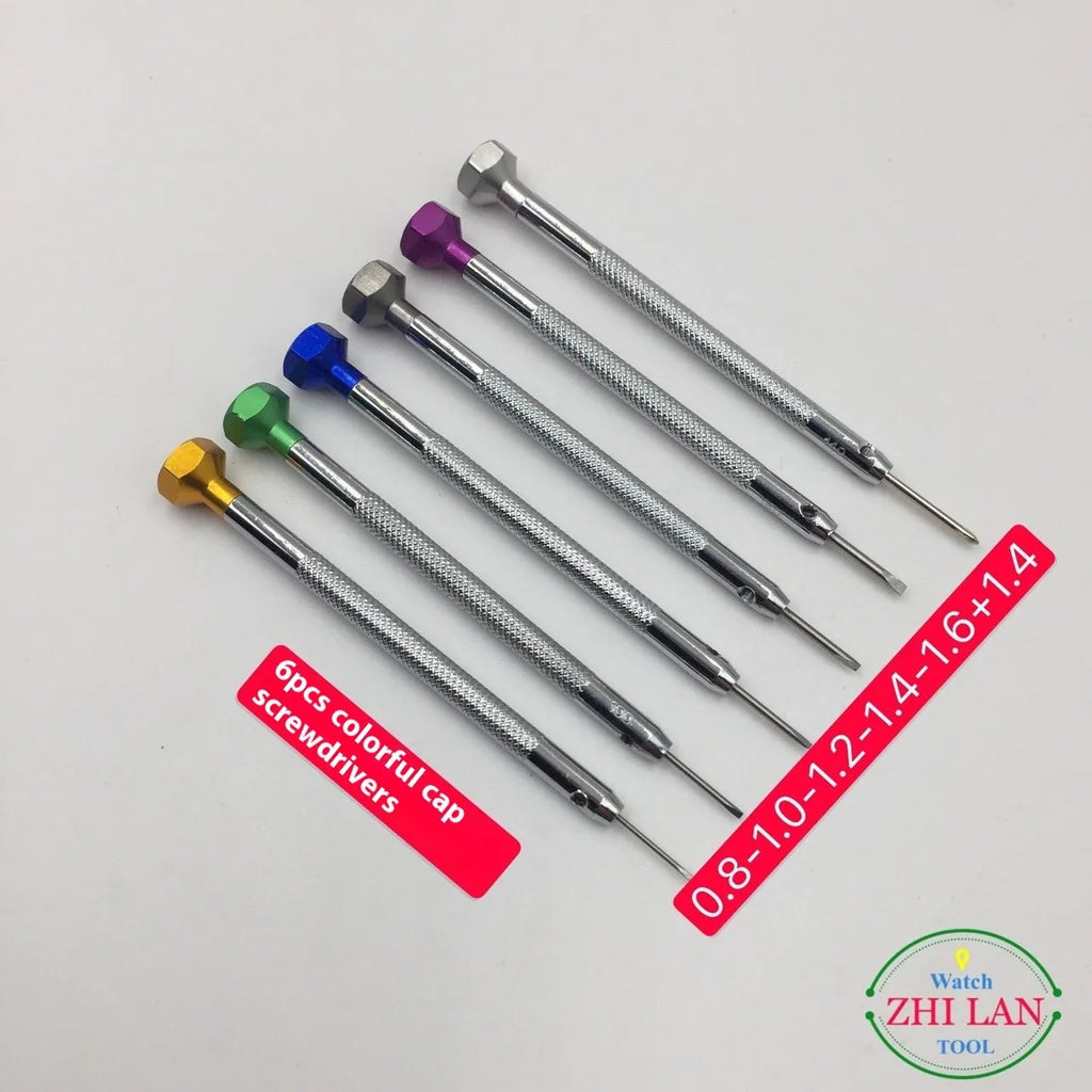 Six colour-coded watch repair screwdrivers with aluminium and copper handles laid out on a surface.