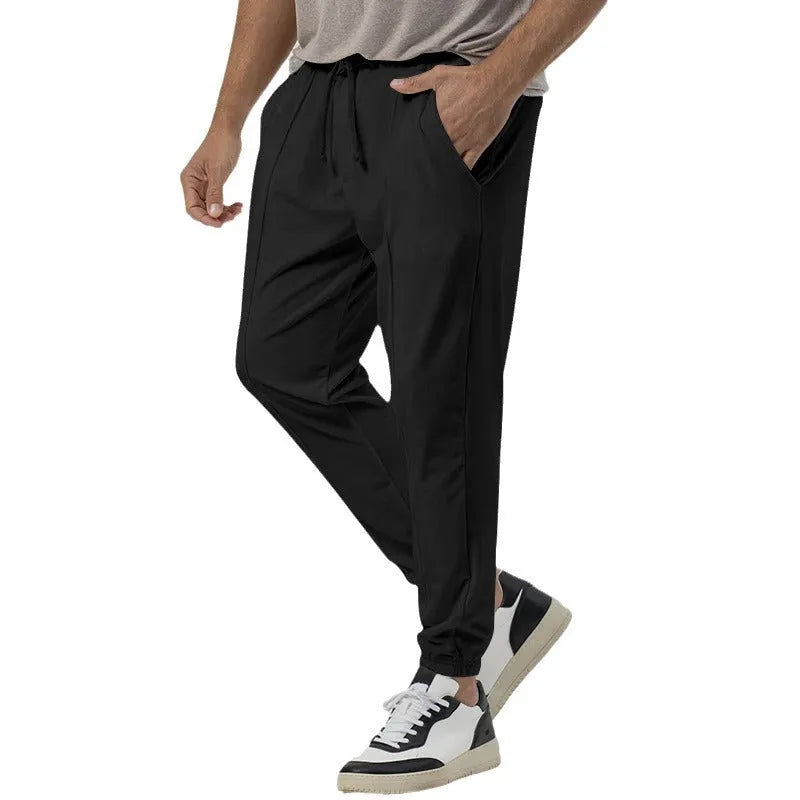Men's grey loose tapered track sweatpants on a hanger, showing straight-leg design.