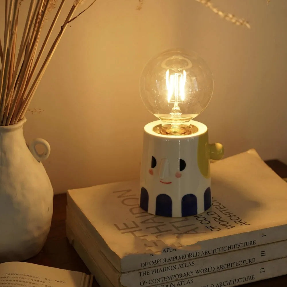 Handmade ceramic bedside lamp with a ball headlight design on a nightstand.