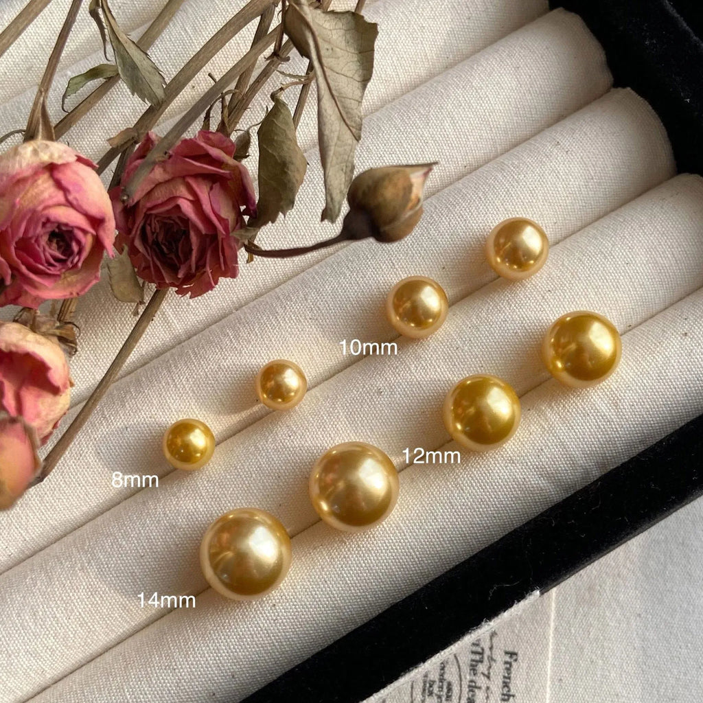 A pair of large geometric silver stud earrings with a central pearl and an eight-point star design detail.