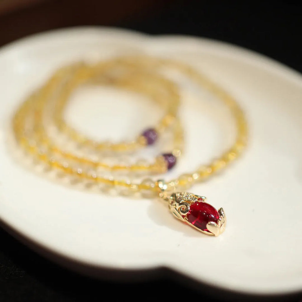 Handmade gold rutilated quartz bracelet with three-circle Chinese design and hanging chopsticks.