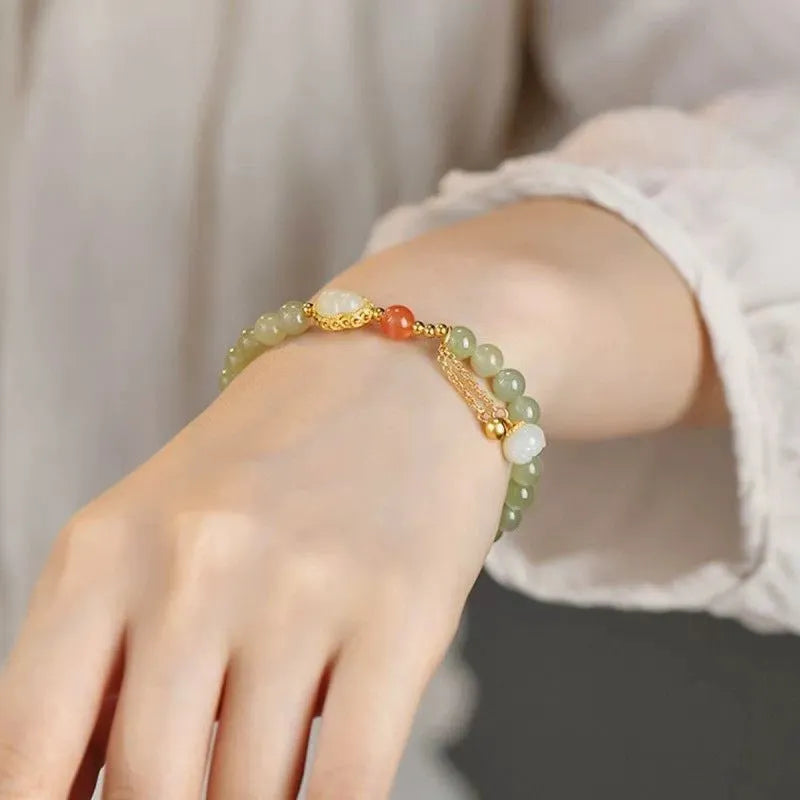 Jade women's bracelet with gold-plated fu character and a central gourd charm on wrist.