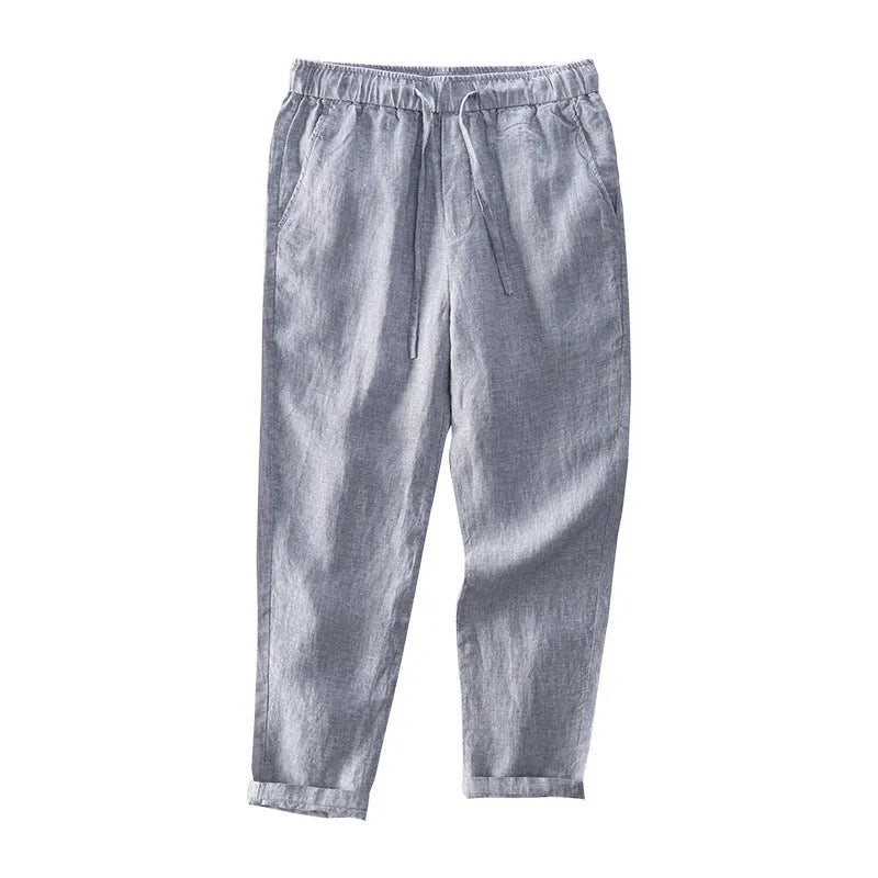 Men's straight-leg linen trousers in light grey, laid flat to show the mid-waist and tailored cut.