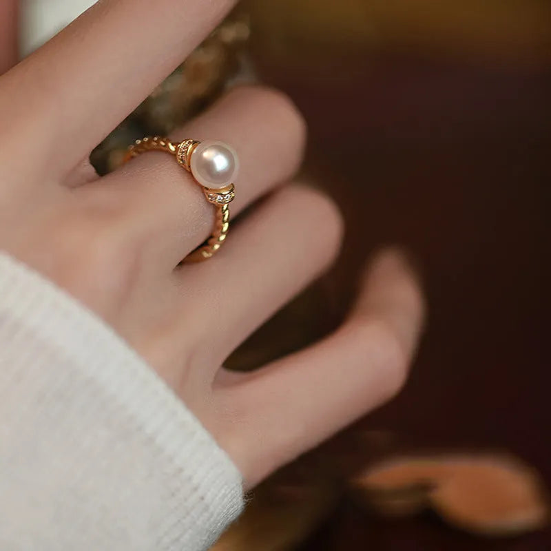 Adjustable copper ring with antique twist design and inlaid pearl in gold finish.