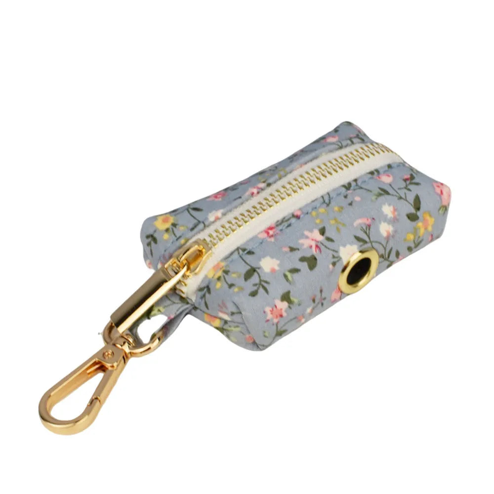 Blue floral patterned dog collar and matching leash, bow, vest, and poop bag set on a white background.