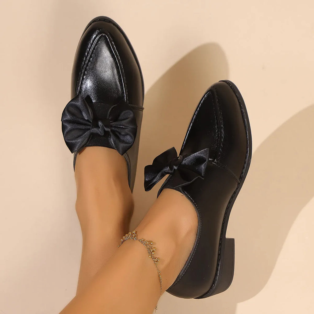 Women's simple slip-on shoe in a British-style leather look with a choice of buckle or bow decoration on the upper.