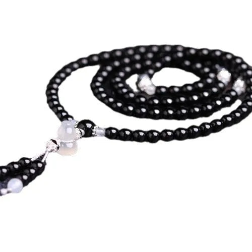 Natural black and red agate 108 bead bracelet with geometric shapes on a wrist.