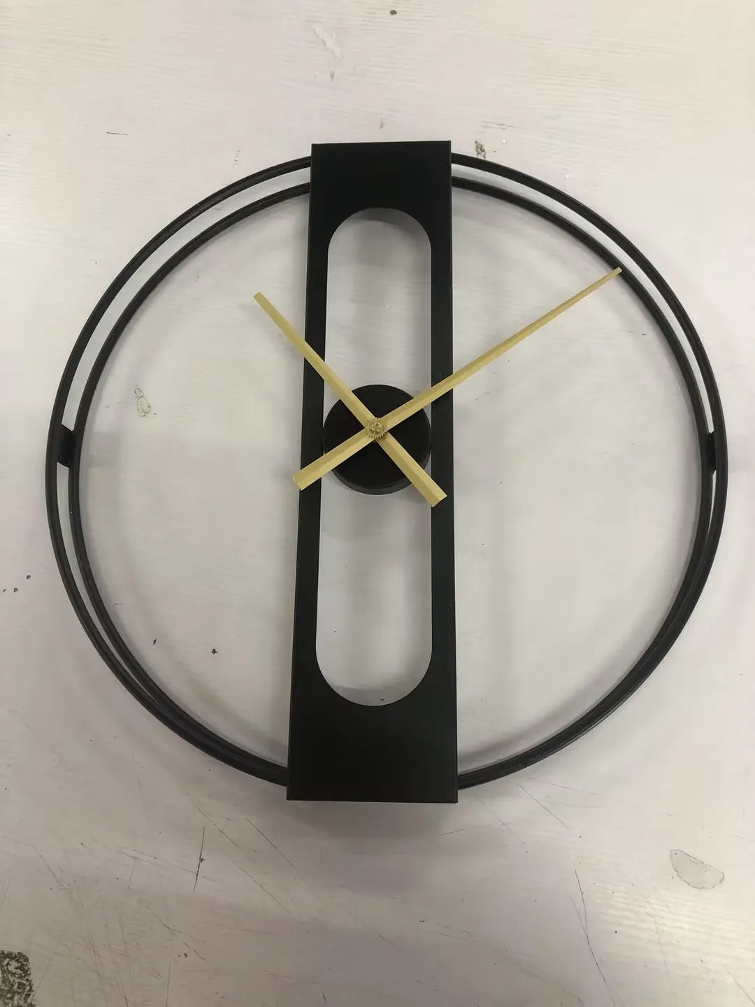 Round metal wall clock with 50 cm diameter in black or gold finish on a wall