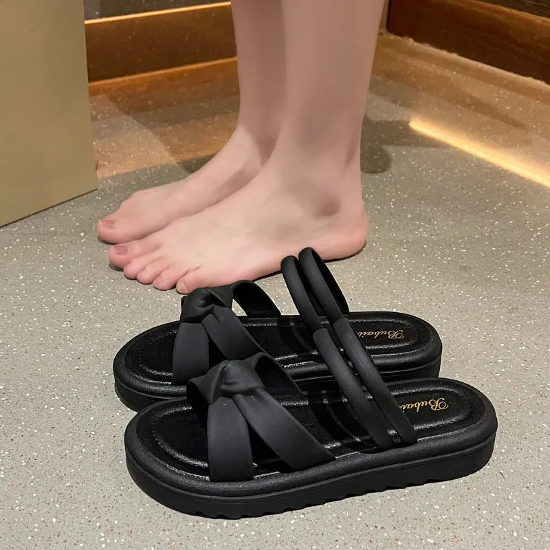 Women's black PVC sandals with soft back, floral detail, and a thick height-increasing sole.