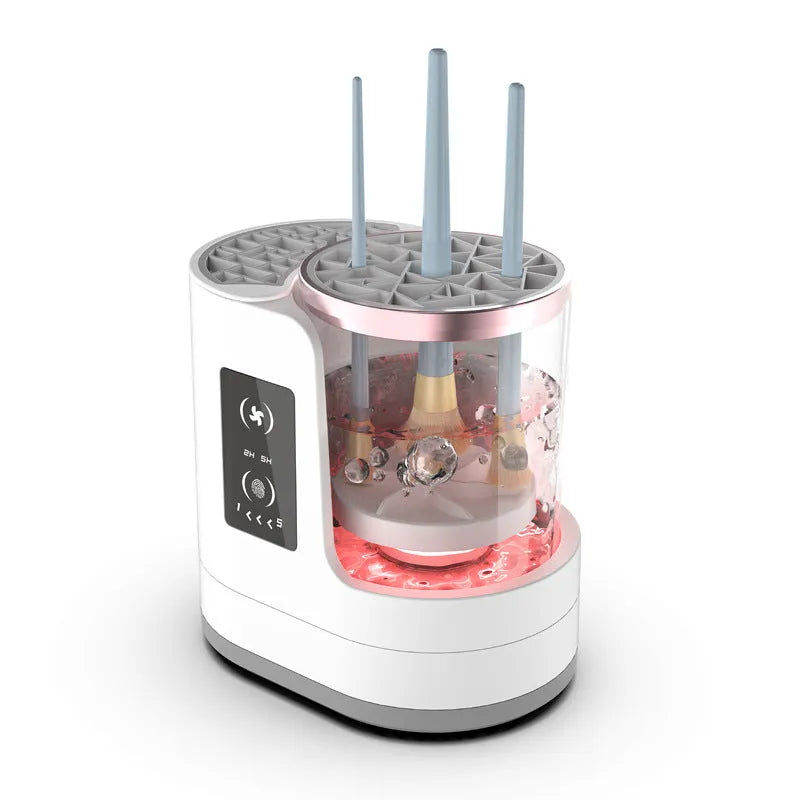 White electric makeup brush cleaner with drying chamber on a table, next to makeup brushes.