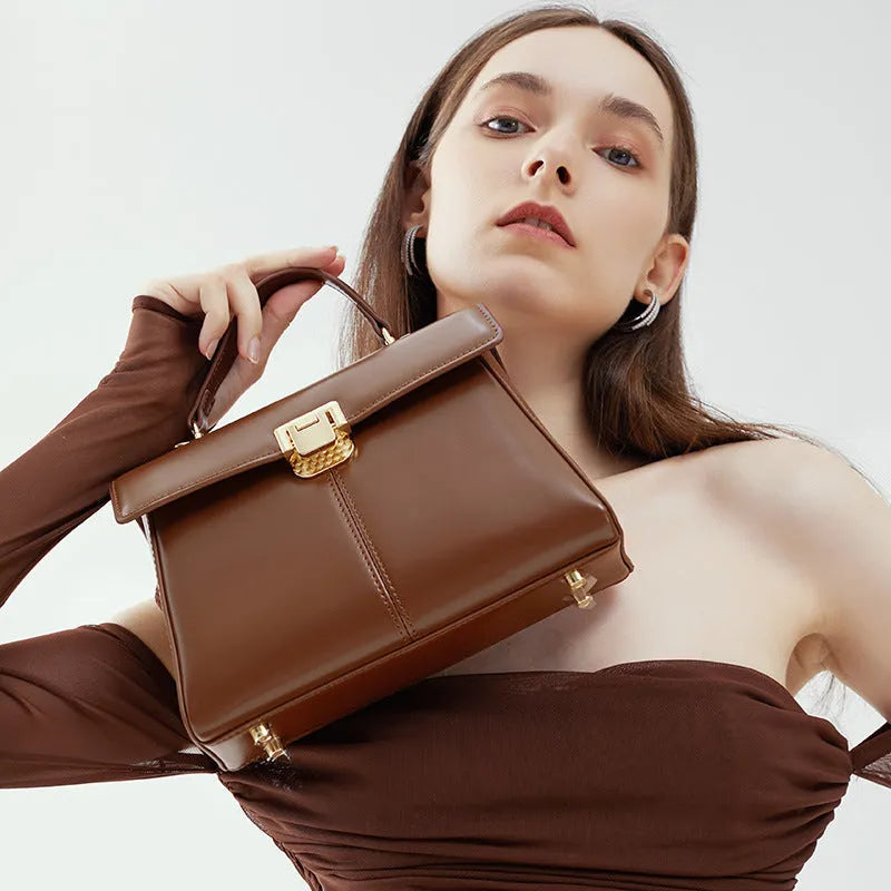 Women's black leather shoulder bag with vachette clasp showing interior zippered compartments