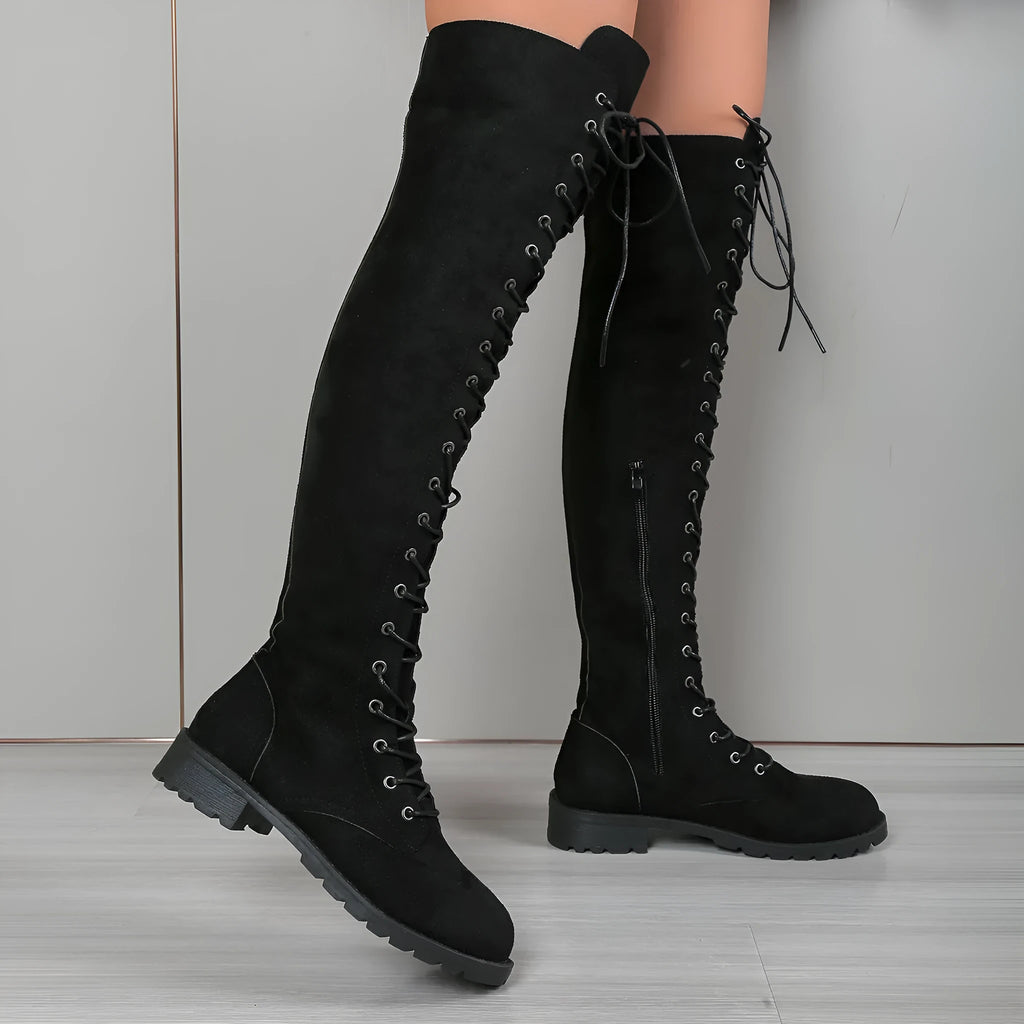 Black lace-up over-the-knee flat boots with a round toe, shown on a model.
